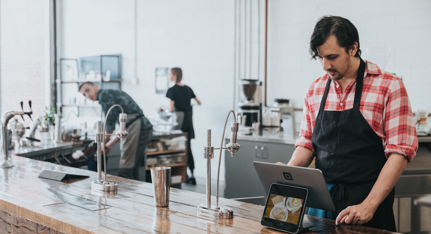 A shop owner taking an order on a tablet